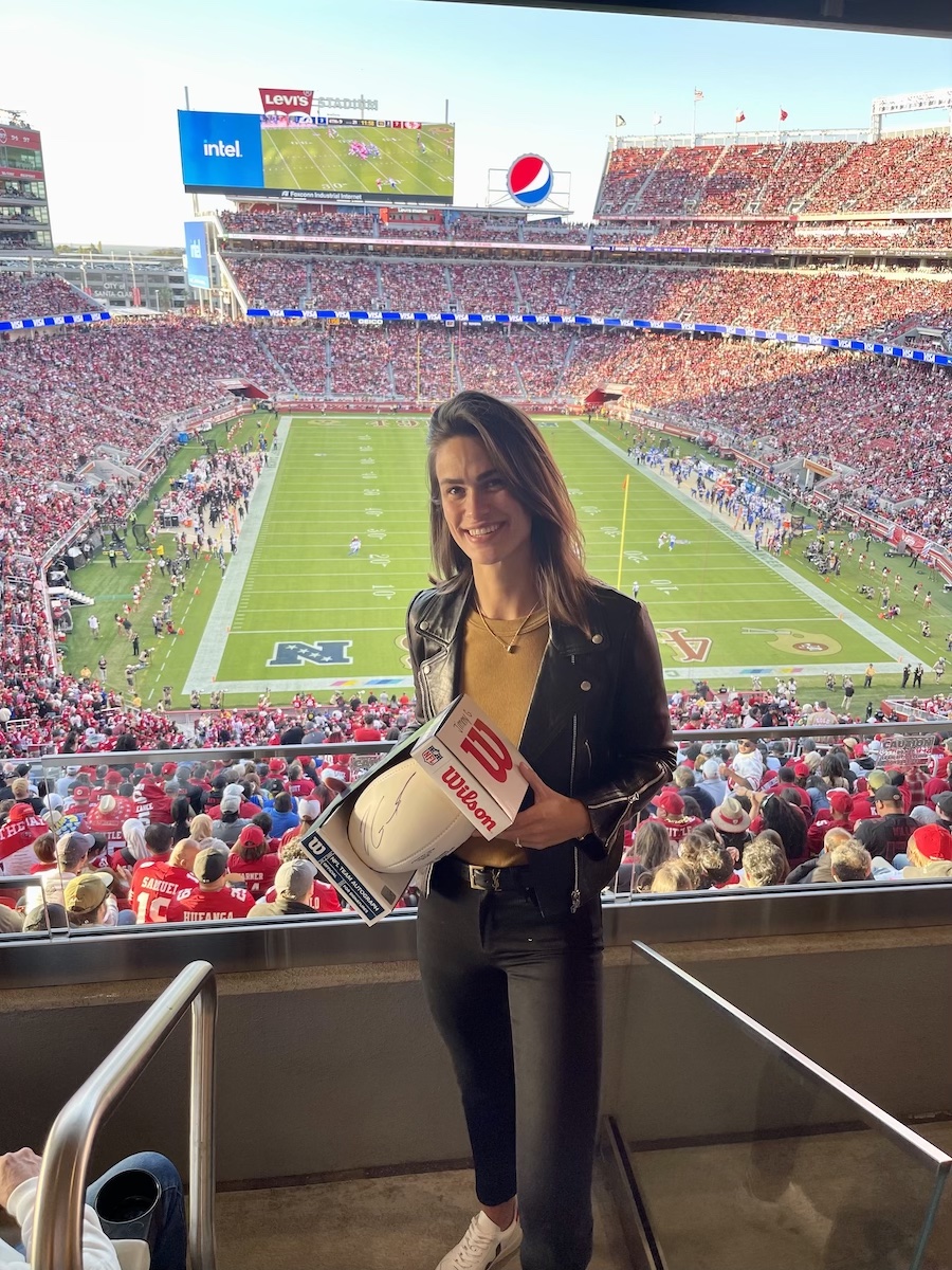 woman holding signed football at a football game