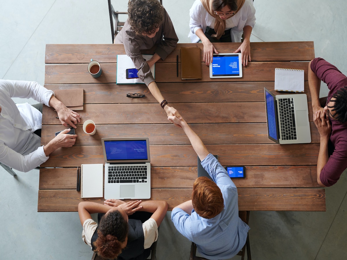 a group of people around a table with laptops developing outreach strategy